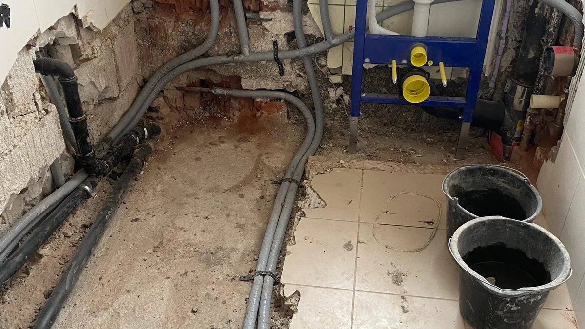Freigelegte Wasserleitungen im aufgestemmten Boden nach einem Leck
