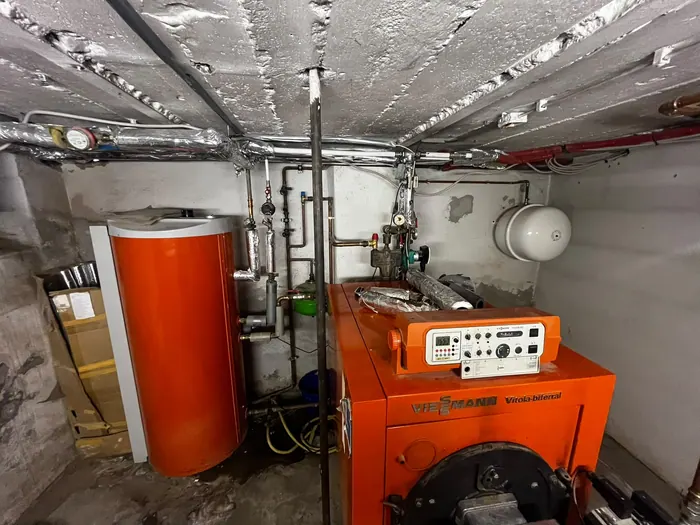 Alter Öl-Heizkessel mit Speicher im Keller vor dem Austausch
