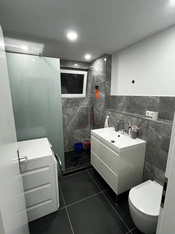 Bad in grauer Marmoroptik mit Waschtisch, Wand-WC und Dusche