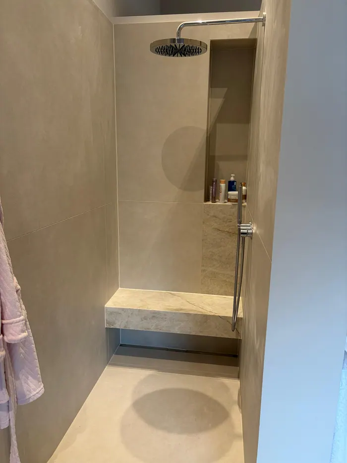 Bodengleiche Dusche in fugenloser Beigeoptik mit Ablagenische