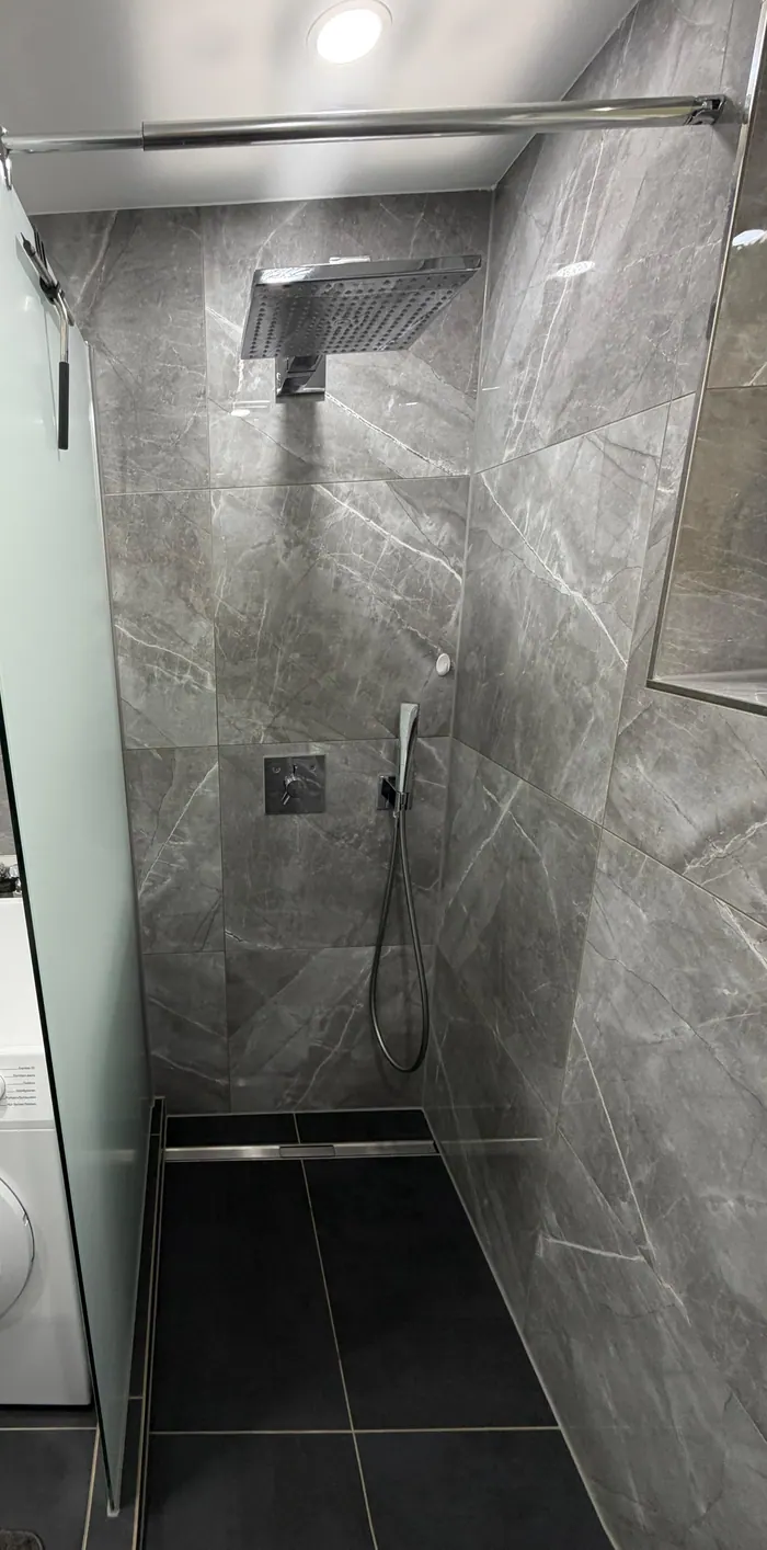 Bodengleiche Dusche in grauer Marmoroptik mit Regendusche und Glaswand
